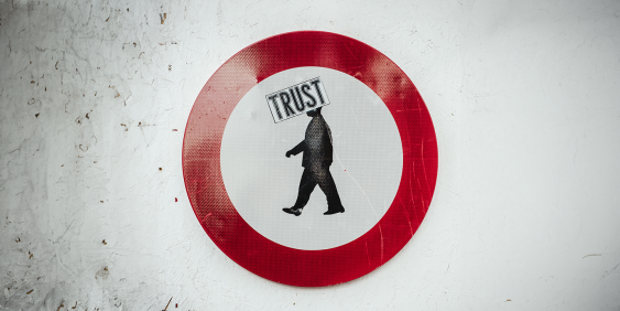 Red circle sign with a man in it and 'Trust' written across his head