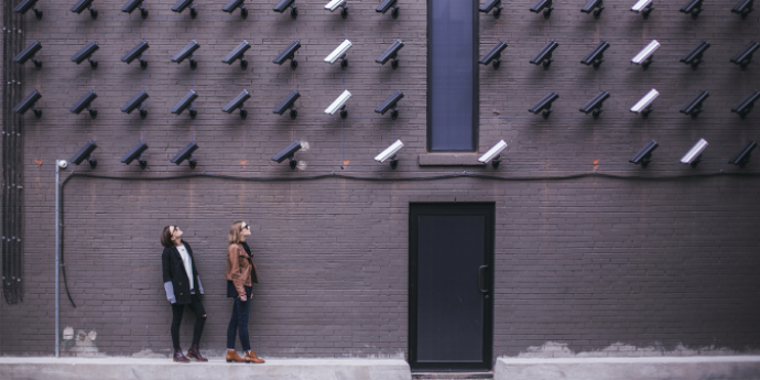 Two women looking up at security cameras on a brick wall