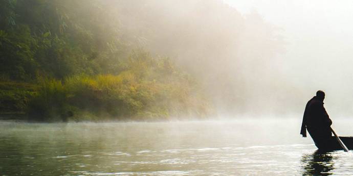 Mist over lake with man in fishing boat