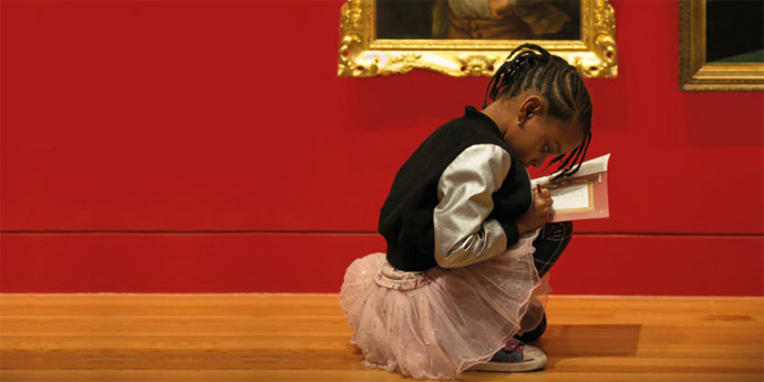 Young girl reading book in museum