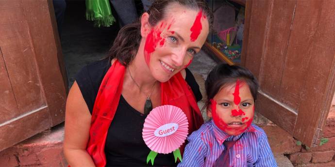 Zoe Dryden with face paint sitting next to a child