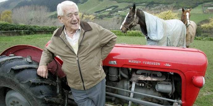 Sir Rod Weir on his farm standing next to a tractor