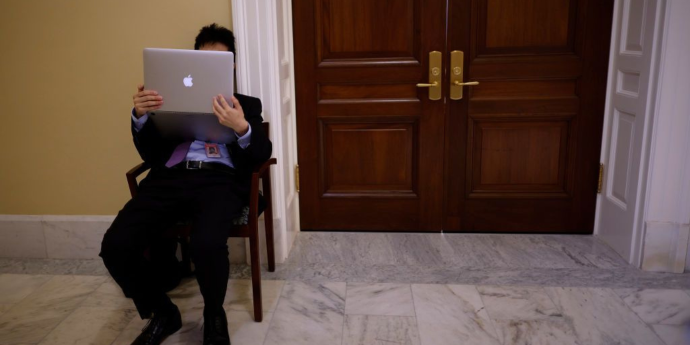Man sitting in chair holding a Mac laptop