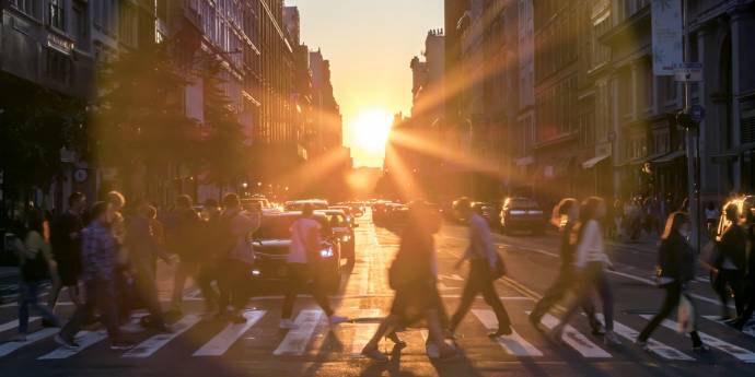 People crossing a zebra crossing with the sun setting in the background