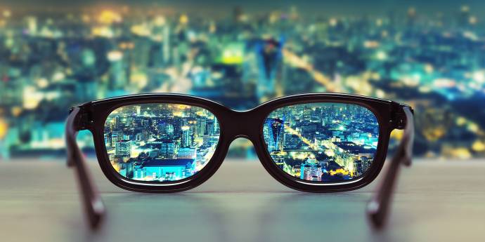 reading glasses on a table with view over city at night