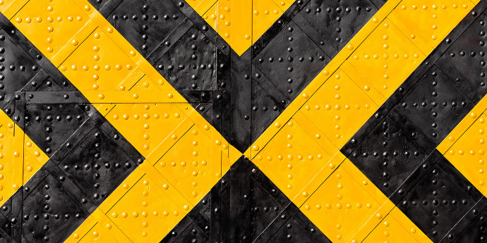 Yellow and black diagonal lines on riveted metal sheet